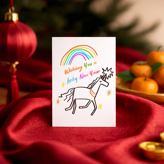 Whimsical New Year card showing a unicorn under a rainbow with the text “Wishing You a Lucky New Year.” The childlike drawing style creates a fun and magical feeling.