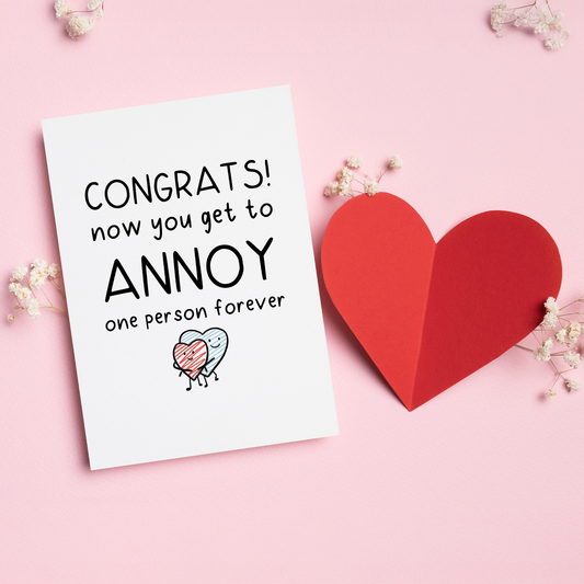 Congrats, You’re Taken is a funny love card for couples who know that love means choosing the same person and annoying them forever. With a playful illustration and cheeky message, this card is perfect for Valentine’s Day, engagements, anniversaries, or just reminding your partner that they’re officially stuck with you.