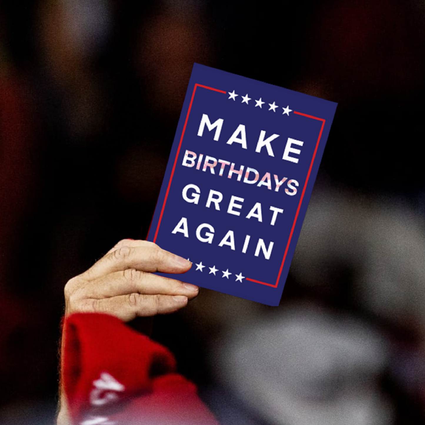 Hand holding a greeting card with the phrase 'Make Birthdays Great Again' in bold patriotic colors.