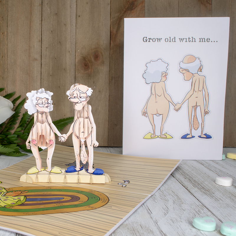 A cute paper couple holding hands, representing love and togetherness. They are depicted in a funny Valentine's Day pop-up card, showing the stages of love and growing old together.