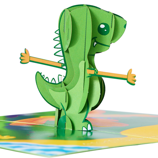 A cute green dinosaur on a green board with a butterfly. A valentine's day card with a pop-up T-rex and arm extenders, with the text "always and forever" written in sand on the beach.