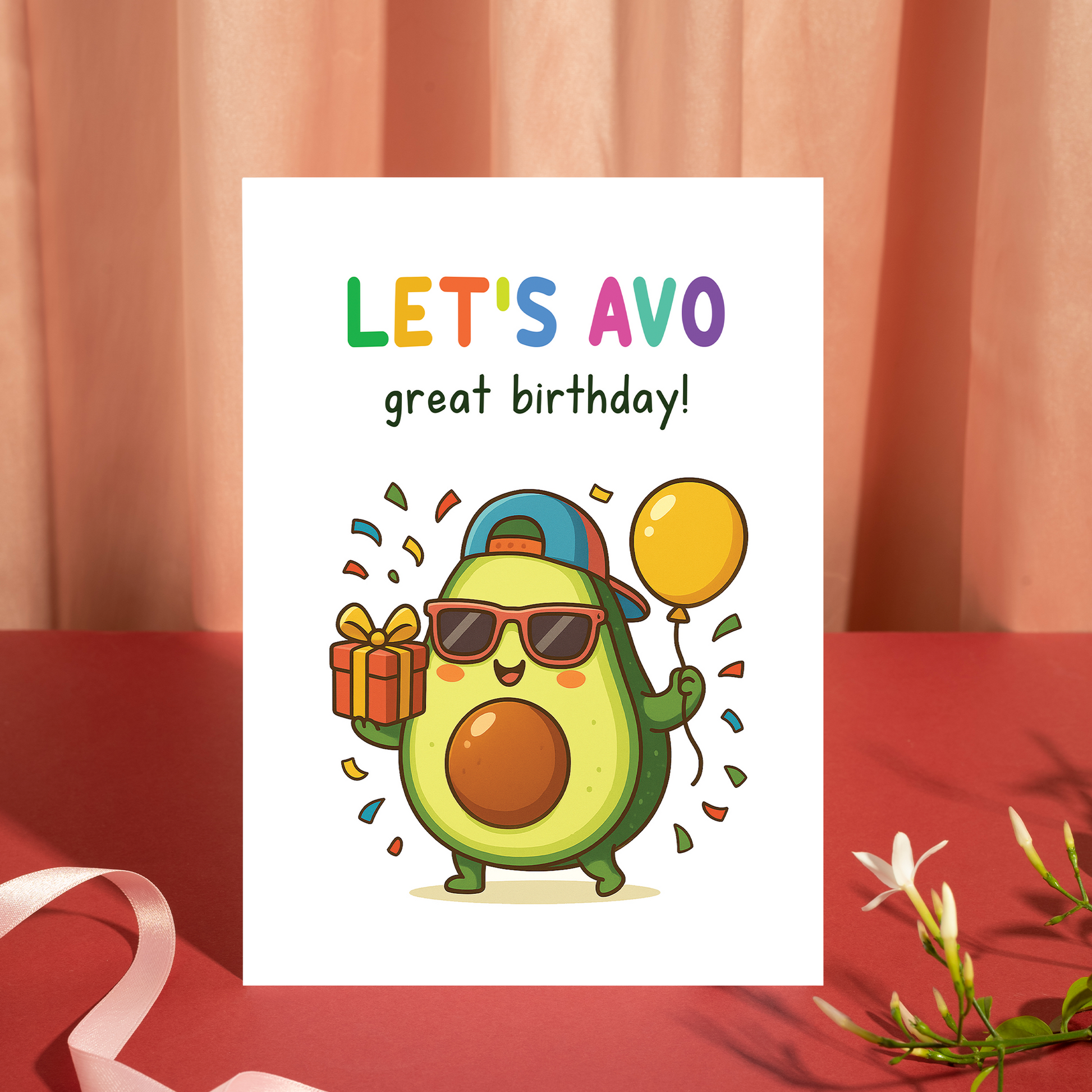 Whimsical birthday card showing a happy avocado holding a wrapped present and a yellow balloon. The playful text “Let’s avo great birthday” delivers a joyful message with a trendy and humorous vibe.