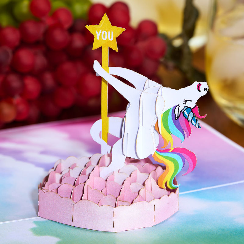 Whimsical pop up birthday card showcasing a unicorn gracefully dancing on a pole, against a vibrant rainbow backdrop.