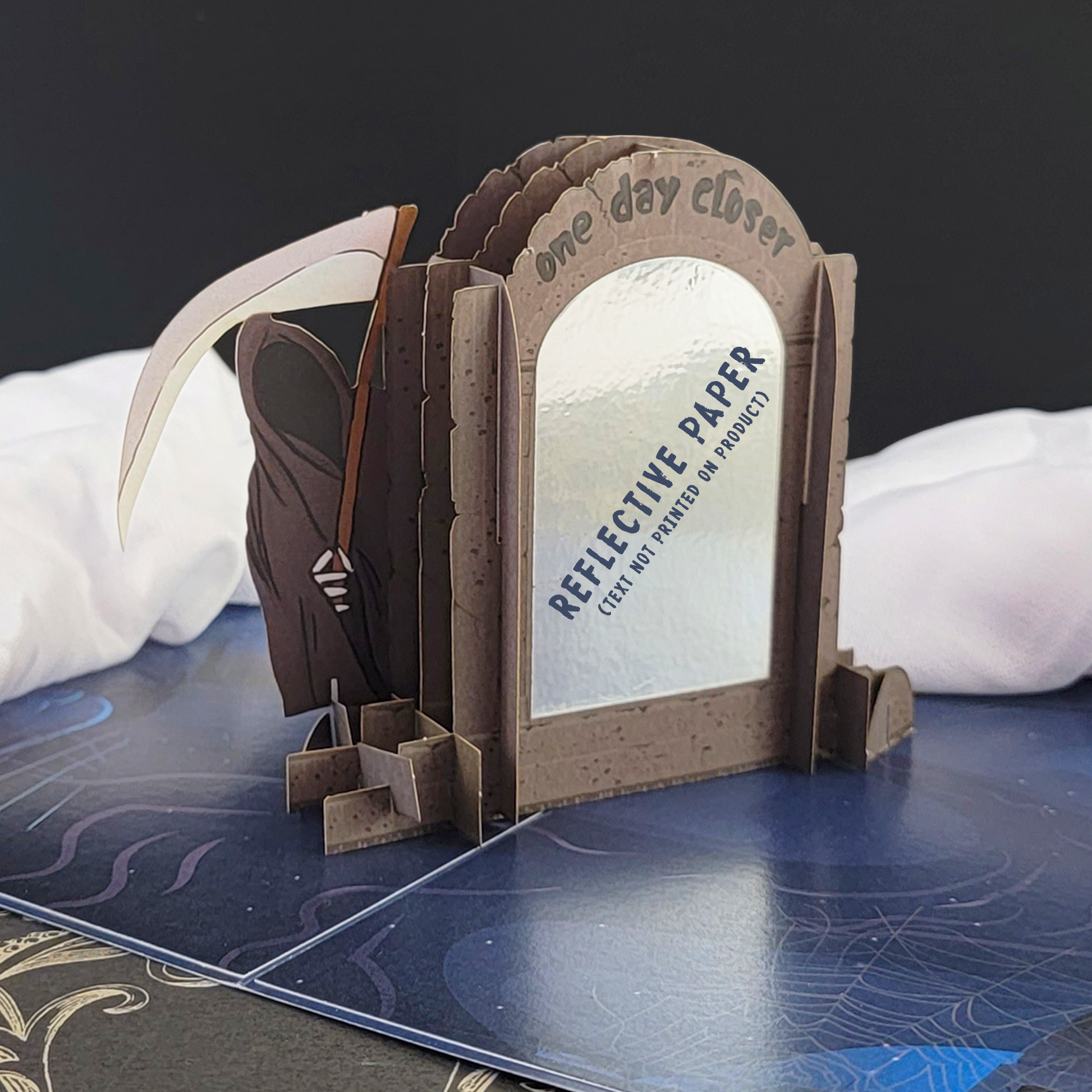 Humorous birthday card featuring Grimp Reaper and a tombstone with a scythe. Engraved text: One day closer.