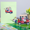 A whimsical pop-up greeting card capturing the delight of two men merrily driving a golf cart, chuckling away.