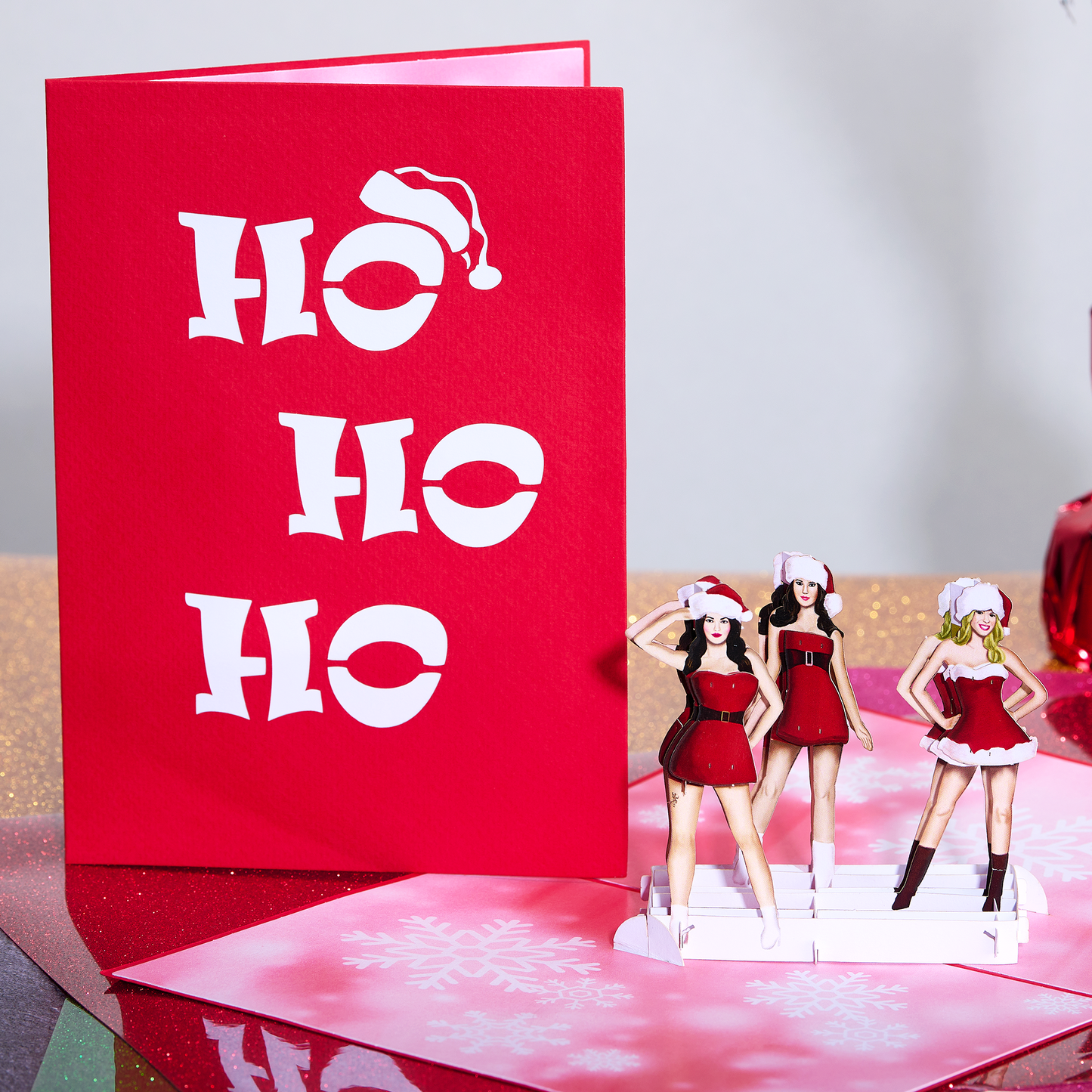 Three lovely ladies dressed as Ms. Santa don playful hats for a hilarious holiday card.
