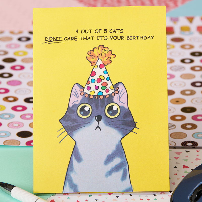 A gray tabby cat wearing a birthday hat on a funny card that says "4 out of 5 cats don't care that it's your birthday". Meow!