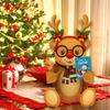 Decorative reindeer with glasses and a scarf holding a 'Let it Snow!' sign in front of a Christmas tree.