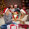 Two children wearing Santa hats exchanging a toy in a festive living room with Christmas decorations.