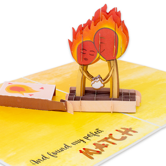 A pop-up card with a fiery background and a couple kissing. The card features an online dating theme with two matchsticks holding hands in a matchbox, accompanied by the text And found my perfect match.