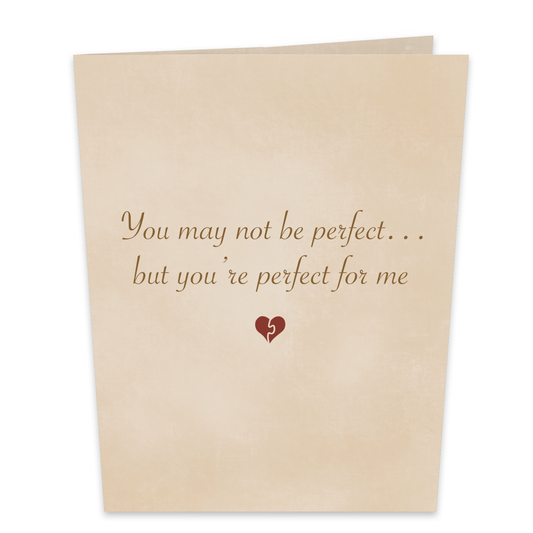A beige greeting card with elegant script text that reads, You may not be perfect... but you’re perfect for me. Below the text is a small heart symbol. The card has a simple, heartfelt design.