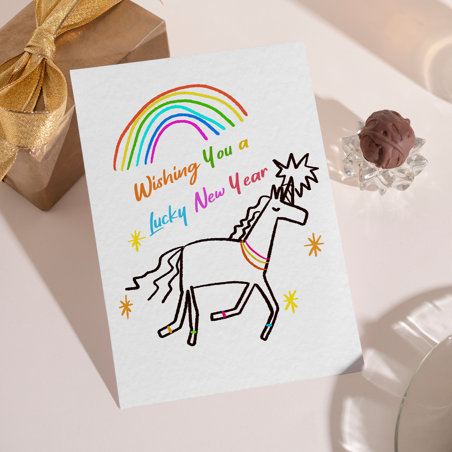 Playful New Year greeting card featuring a unicorn running beneath a rainbow. The colorful artwork symbolizes good luck, happiness, and fresh starts.