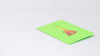 A video shows a pop-up card with a 3D bong design being opened and displayed. The camera pans around to capture the colorful details of the bong illustration, while a real bong and lighter are placed nearby, enhancing the playful theme.