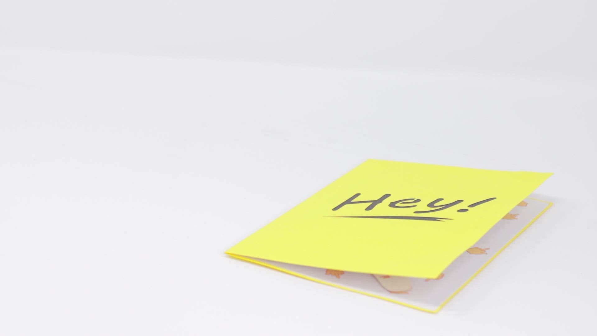 A video shows a pop-up card opening to reveal a 3D hand giving the middle finger. The cover features the word Hey! in bold black on a bright yellow background, adding a playful and cheeky surprise.